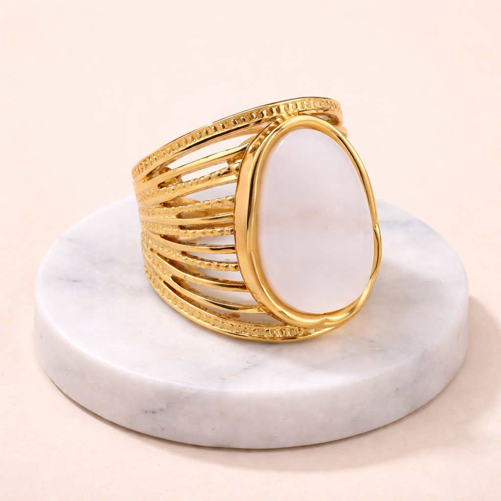Bague ajustable dorée en acier inoxydable avec pierre blanche sur socle en marbre
