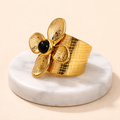 Bague fleur dorée en acier inoxydable avec pierre noire sur socle en marbre