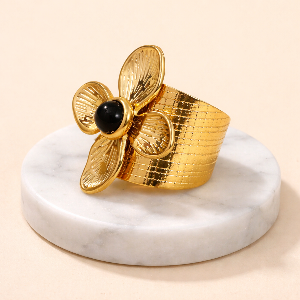Bague fleur dorée en acier inoxydable avec pierre noire sur socle en marbre