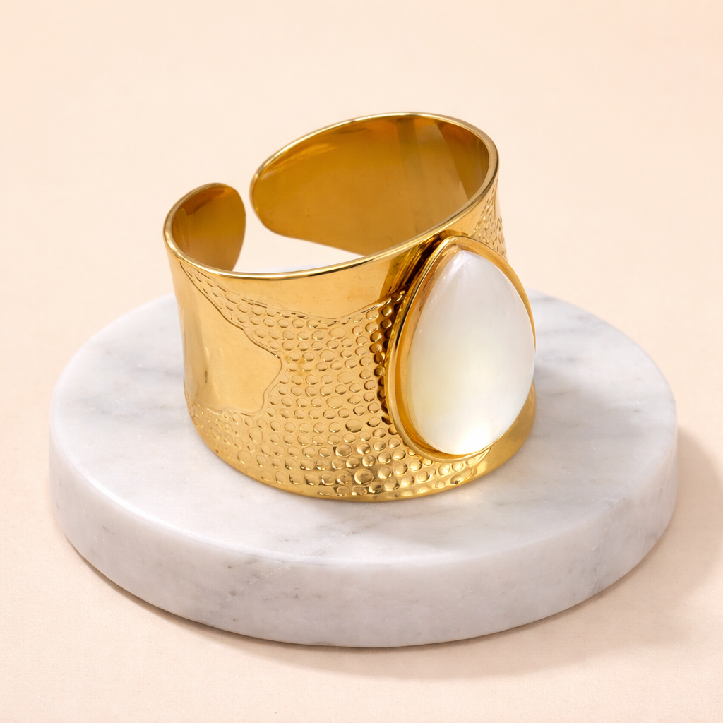 Bague manchette dorée en acier inoxydable avec pierre blanche sur socle en marbre